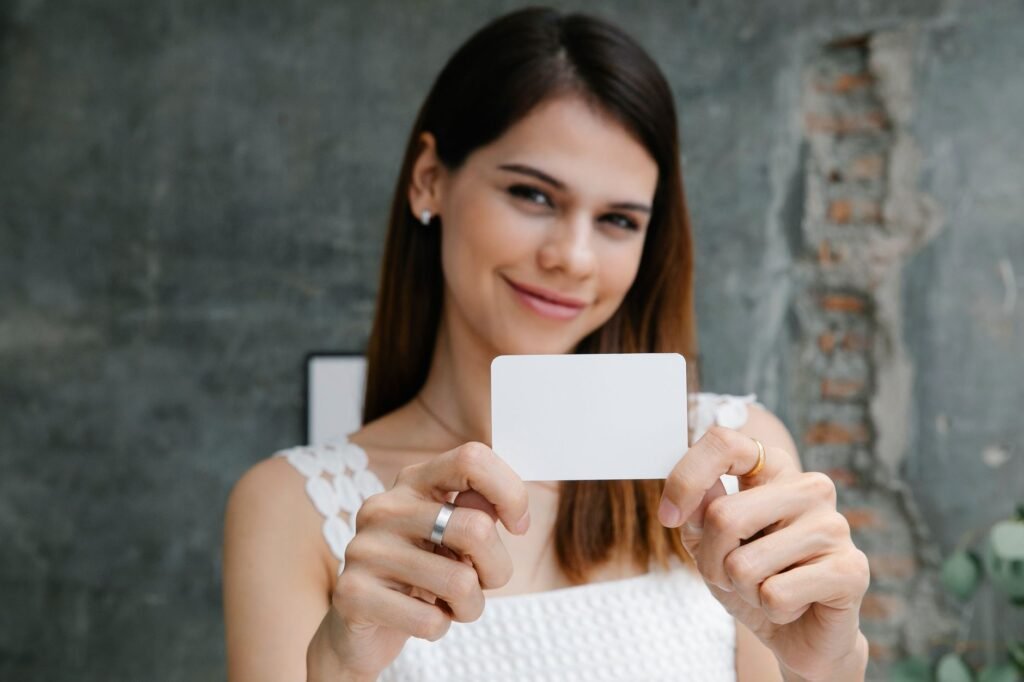 smiling woman holding a blank business card in front of her