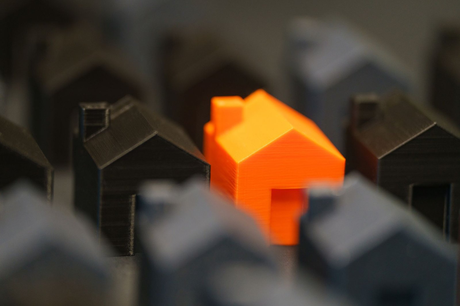 striking orange model house amidst black miniatures