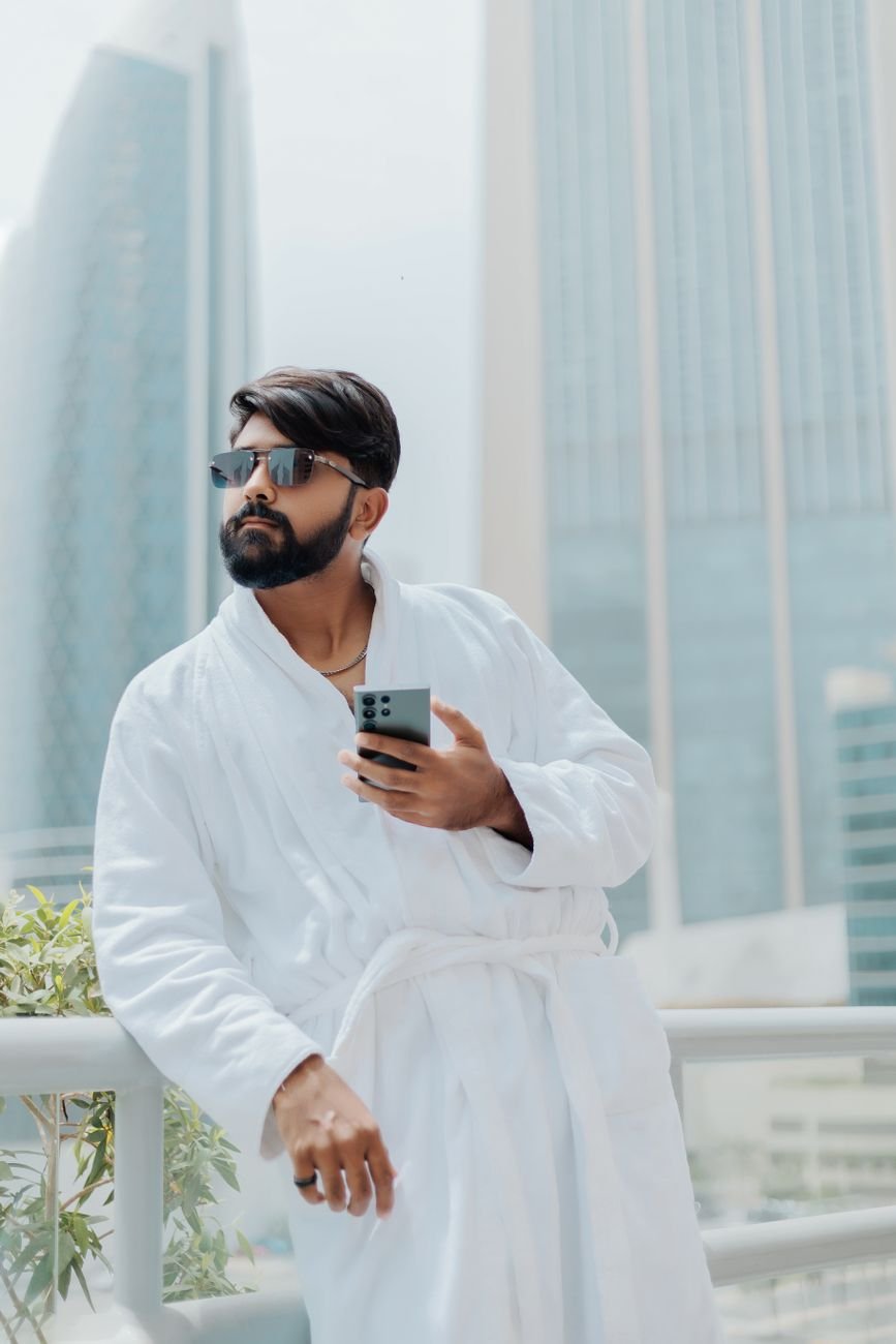 man relaxing on hotel balcony with smartphone