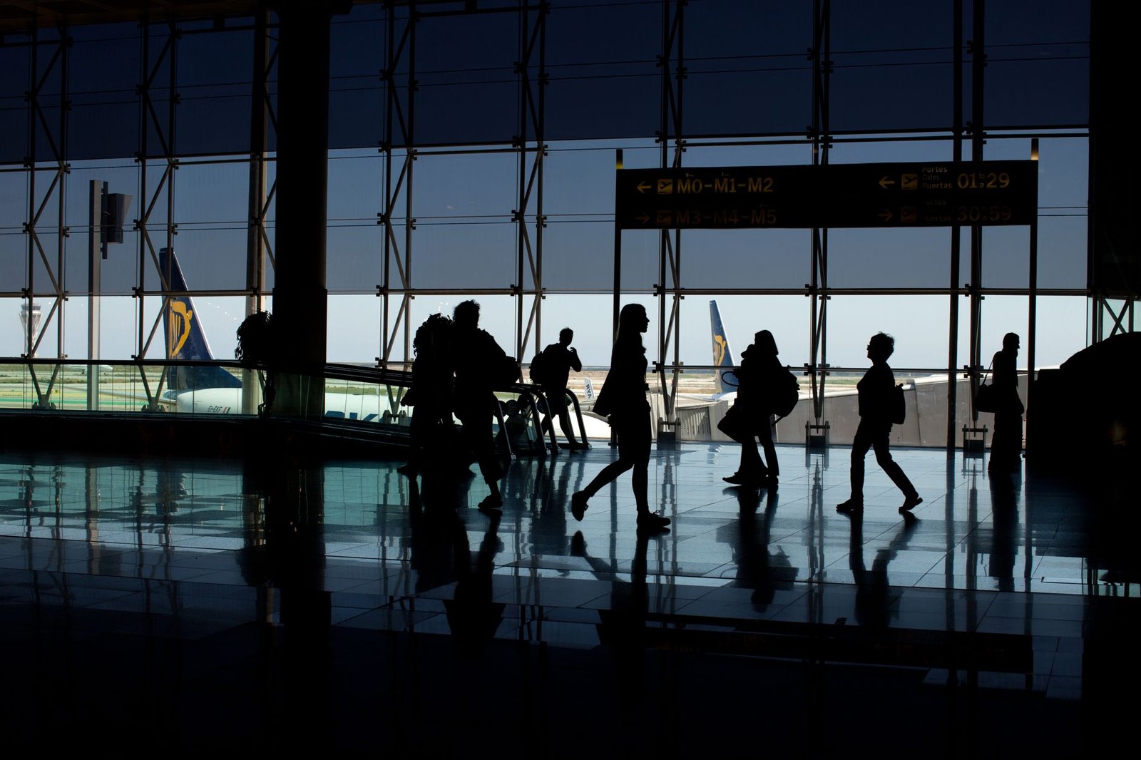Silhouettes of people walking in an airport terminal