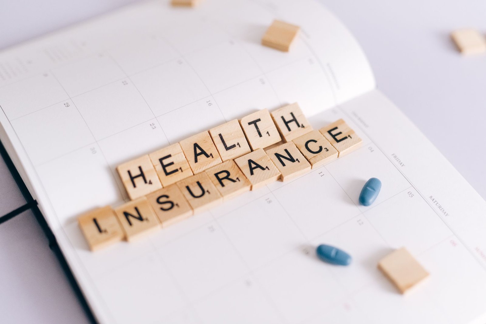 Health insurance Scrabble tiles on a planner with medication pills
