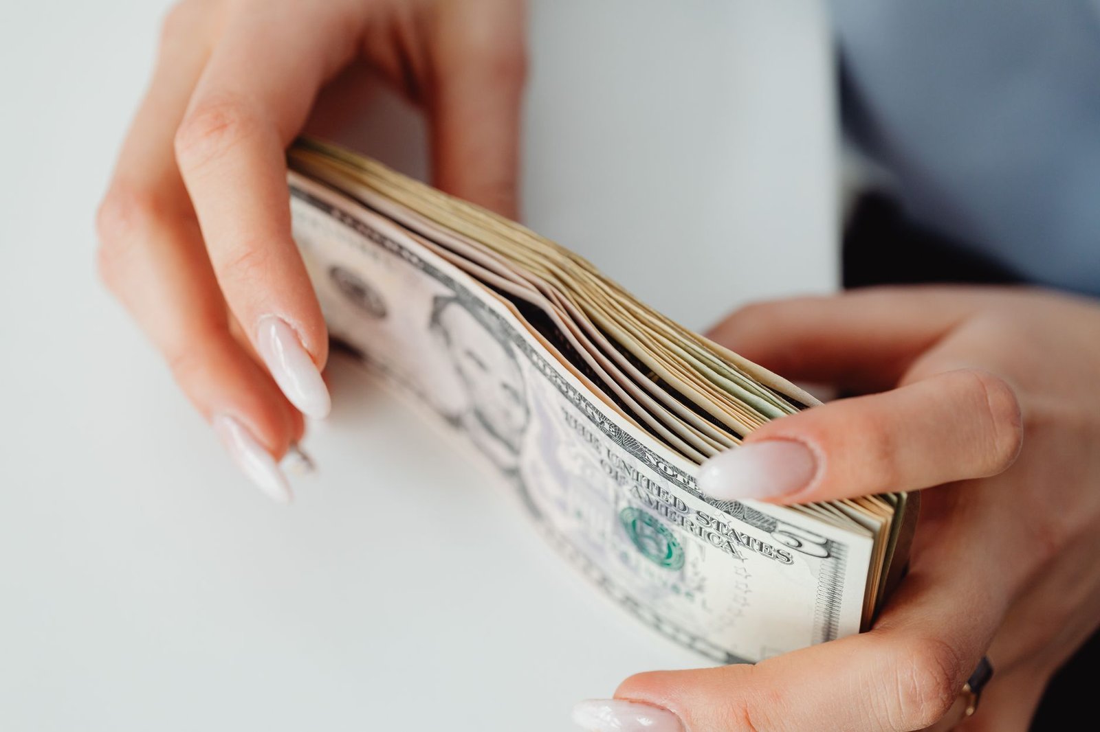 close up shot of a person holding paper money on white surface