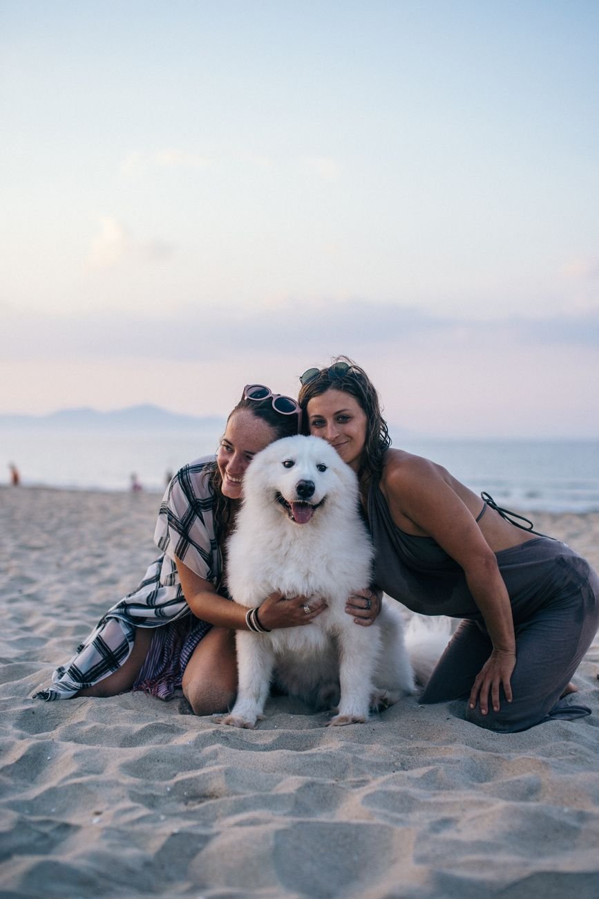 two women and white dog on the beach