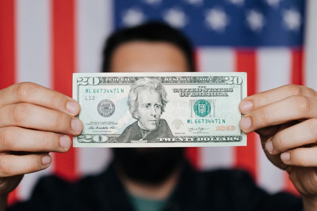 Blurred adult man demonstrating United States paper bill for personal financial operations hiding face on background of USA national flag